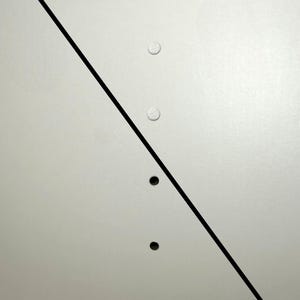 K&ouml;nnte beinhalten: Eine hellgraue Oberfl&auml;che mit den W&ouml;rtern "AFTER" und "BEFORE" in Schwarz. Drei kleine, wei&szlig;e, kreisf&ouml;rmige Objekte befinden sich oberhalb der schwarzen Diagonallinie und drei kleine, schwarze, kreisf&ouml;rmige Objekte darunter.