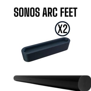 Op de afbeelding: Zwarte Sonos Arc voeten, ontworpen om de Sonos Arc soundbar te verhogen. De afbeelding toont twee zwarte voeten, en de tekst "SONOS ARC FEET" en "(X2)". De soundbar is zichtbaar onderaan de afbeelding.