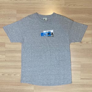 Puede incluir: Camiseta gris con un estampado gráfico azul y blanco que dice "Four Star".