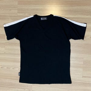 May include: Black v-neck t-shirt with white stripes on the sleeves. The shirt has a small logo on the front that says "RE-THINK FASHION".
