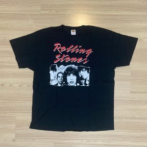 May include: Black t-shirt with a white and red graphic of the Rolling Stones band members and the text "Rolling Stones".
