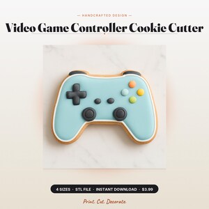 Puede incluir: Una galleta con forma de mando de videojuego decorada con glaseado azul claro, una cruceta negra, dos joysticks negros y cuatro pequeños botones circulares en naranja, azul claro, verde lima y amarillo, delineados con glaseado blanco.