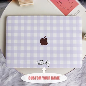 Op de afbeelding: Een lichtpaarse en witte geruite laptophoes met een bruin appel-logo. De naam "Emily" staat in cursief onder het logo. Een tekstballon onderaan zegt "CUSTOM YOUR NAME".