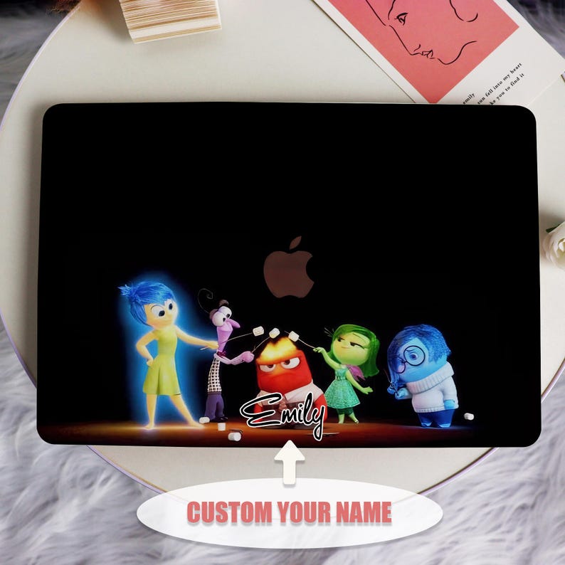 May include: A black laptop skin with a design of the characters from the movie Inside Out. The characters are Joy, Sadness, Fear, Disgust, and Anger. The characters are arranged in a line, with Joy on the left and Anger on the right. The characters are all smiling and holding marshmallows on sticks. The text 'Emily' is written in pink below the characters. The text 'CUSTOM YOUR NAME' is written in white below the laptop skin.