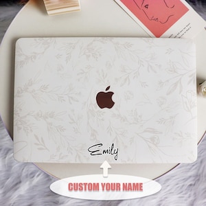 Könnte beinhalten: Weiße Laptop-Haut mit einem Blumenmuster und einem silbernen Apple-Logo. Die Haut hat einen personalisierten Namen, "Emily", aufgedruckt. Der Text "CUSTOM YOUR NAME" ist unter dem Laptop aufgedruckt.