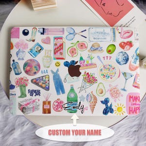 May include: A white laptop with a colorful sticker design. The stickers feature various images, including a pineapple, a watermelon, a camera, a pair of sunglasses, a disco ball, a pair of boots, a tennis racket, a seashell, a turtle, a balloon, a sun, a pomegranate, a bunch of flowers, a green avocado, a glass of martini, a bowl of cereal, a pair of overalls, a phone, a bottle of water, a pair of green rain boots, a newspaper, a box, a heart, a smiley face, a pair of scissors, a hat, a flamingo, a strawberry, a pair of dice, and the text "The Breakers", "777", "444", "Spark", "Fullness of Joy", "Check", "Make today happy", and "Emily".