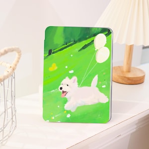 Può includere: Una custodia rettangolare con un'allegra illustrazione di un cane bianco che corre su un campo verde brillante, tenendo due palloncini bianchi. Lo sfondo raffigura un paesaggio verde con alberi e fiori.