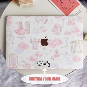 Könnte beinhalten: Eine weiße Laptop-Haut mit einem rosa und goldenen Design mit Wolken, Sternen und einem Schloss. Der Text "Emily" ist in schwarzer Kursivschrift am unteren Rand der Haut geschrieben. Die Haut ist mit einem Namen Ihrer Wahl anpassbar.