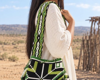 Puede incluir: Un bolso tipo cubo con un patrón geométrico de estrella en negro, verde lima y blanco. El bolso cuenta con una correa de hombro tejida a juego y una borla lateral compuesta por hilos negros, blancos y verdes en todo el diseño.