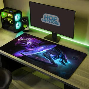 May include: A black rectangular mousepad featuring a purple and blue fantasy creature design with the word "KHAZIX" in white. The computer monitor displays the text "HOE GIFTSTORE". A computer tower and speaker are visible.