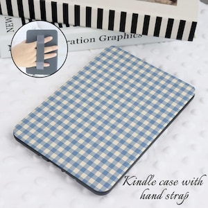 Peut inclure: Une coque pour Kindle à motif vichy bleu et blanc avec une dragonne noire.  "Kindle case with hand strap" est écrit en blanc sous la coque.