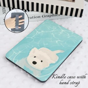 May include: A blue and white Kindle case with a white dog illustration. The case has a gray hand strap.