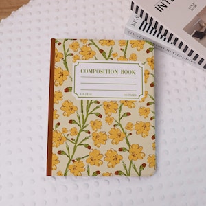 May include: A composition book with a floral design featuring yellow flowers and green stems on a cream background. The cover reads "COMPOSITION BOOK" with space for a name and the word "COLLEGE" and "100 PAGES". The spine is brown.