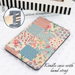 May include: Kindle case with a patchwork design featuring floral and polka dot patterns in shades of pink, blue, and cream. The case includes a hand strap for secure handling. The text "Kindle case with hand strap" is visible.