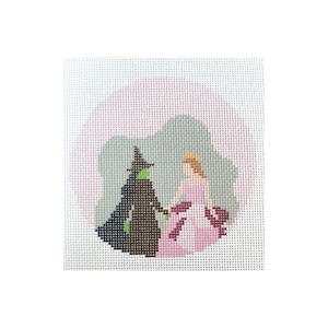 Op de afbeelding: Een naaldkunstdoek met een fantasierijke scène van een groene heks en een prinses die hand in hand staan voor een roze en blauwe achtergrond.