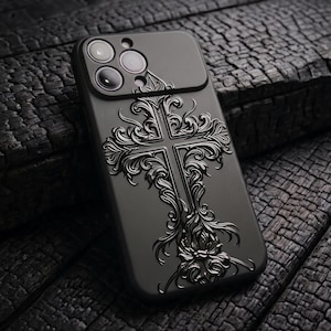 Könnte beinhalten: Eine mattschwarze Smartphone-Hülle mit einem erhabenen, geprägten Kreuzdesign und komplizierten, geschwungenen Filigranmustern. Die Hülle verfügt über einen Ausschnitt für eine Kamera mit drei Objektiven und behält eine einheitlich dunkle Ästhetik bei.