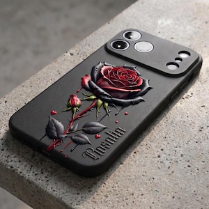 Puede incluir: Una funda de smartphone negra con un diseño tridimensional en relieve de una gran rosa roja con pétalos oscuros, un capullo más pequeño y tallos verdes. El nombre Rosalia está grabado en letra gótica, acompañado de pequeños corazones rojos.
