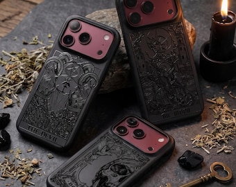 Peut inclure: Trois coques de smartphone noires arborant des motifs de cartes de tarot. Une coque représente Le Diable, une autre La Lune, et la troisième La Mort. Chaque coque possède un module photo rouge foncé et des gravures noires détaillées.