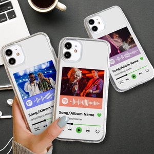 Puede incluir: Tres fundas transparentes para teléfono con fondo blanco y un diseño de reproductor de música similar a Spotify. Cada funda presenta una banda o artista diferente actuando en el escenario. Las fundas tienen botones de reproducción, pausa y avance.