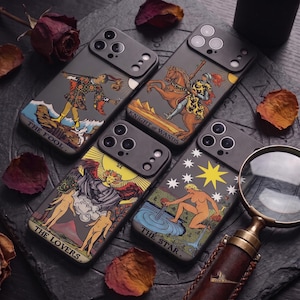 May include: Four black smartphone cases featuring tarot card illustrations. The designs include The Fool, Knight of Wands, The Lovers, and The Star. Each case has a camera cutout and displays the card name in white text at the bottom of the graphic.