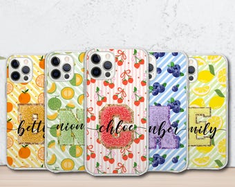 May include: Five phone cases with fruit and initial designs. The cases feature oranges, cantaloupe, cherries, blueberries, and lemons. Each case has a different initial with a glittery, textured appearance and a script name.