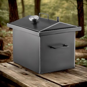 May include: A black metal smoker with a hinged lid and a built-in thermometer. The smoker has a handle on the side and is sitting on a wooden surface.