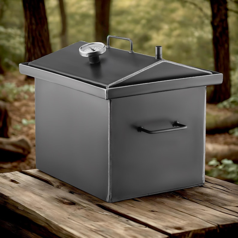May include: A black metal smoker with a hinged lid and a built-in thermometer. The smoker has a handle on the side and is sitting on a wooden surface.