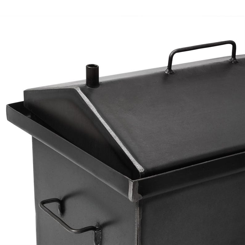 May include: Black metal smoker with a hinged lid and a handle on the top. The smoker has a small vent pipe on the top.