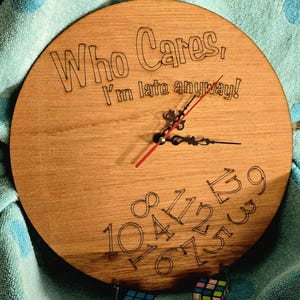 May include: A wooden clock with the text "Who Cares, I'm late anyway!"  The clock face has black numbers 1 through 12 and the hands are black with a red second hand.