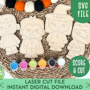 May include: Wooden Halloween character cutouts of Frankenstein, a vampire, a witch, and a mummy. The image includes paint pots in various colours, a decorative garland, and the text "SVG FILE" and "SCORE & CUT".