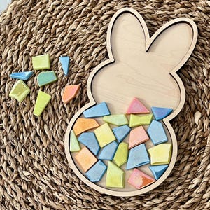 May include: A wooden bunny-shaped tray with a mosaic of colorful tiles inside. The tiles are in shades of blue, yellow, orange, and pink.
