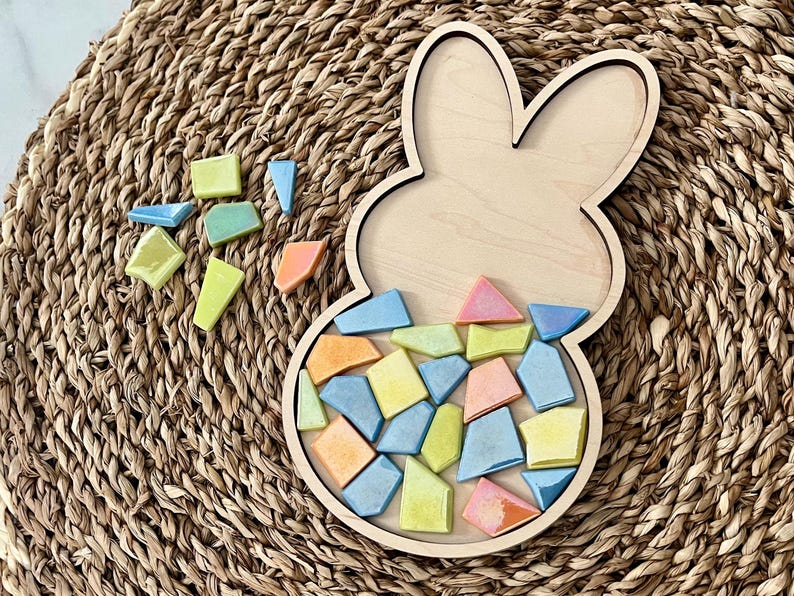 May include: A wooden bunny-shaped tray with a mosaic of colorful tiles inside. The tiles are in shades of blue, yellow, orange, and pink.
