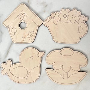 May include: Four unfinished wooden cutouts of spring-themed designs: a birdhouse, a watering can with flowers, a bird, and a flower. The cutouts are ready to be painted.