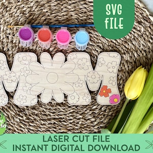 Puede incluir: Un recorte de madera de la palabra "MOM" con un diseño floral. Las letras están rodeadas de una estera de paja tejida y hay cuatro pequeños frascos de pintura en el fondo. El texto "LASER CUT FILE INSTANT DIGITAL DOWNLOAD" está en la parte inferior de la imagen.