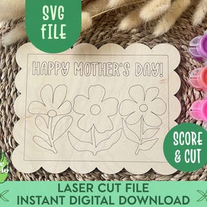 May include: A laser cut wooden sign with a scalloped edge, featuring the text "HAPPY MOTHER'S DAY!" and three stylized flower designs. The sign is ready for painting with included paint pots in pink, red, purple, and blue.