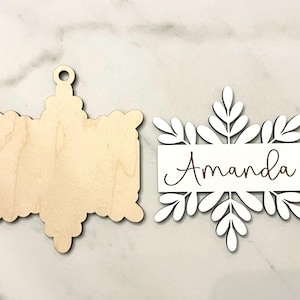 May include: Two unfinished wooden ornaments, one shaped like a snowflake with the name "Amanda" engraved on it, and the other shaped like a star.