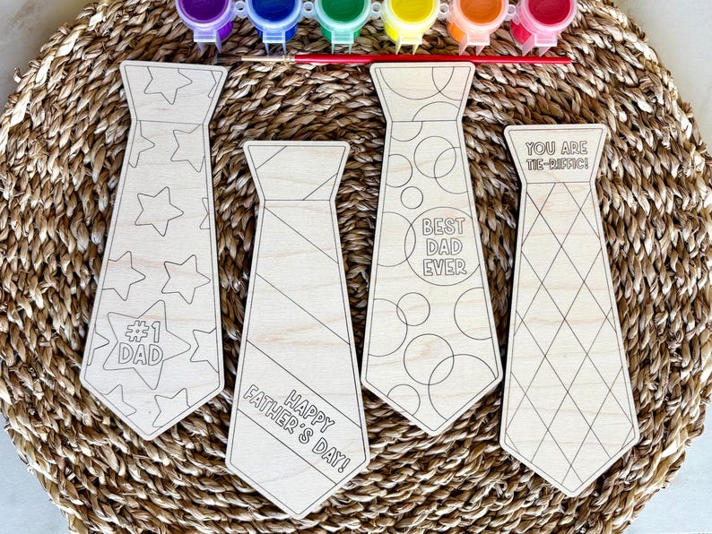 May include: Wooden tie-shaped craft kits with various designs and text, including "#1 Dad", "Happy Father's Day!", "Best Dad Ever", and "You Are Tie-riffic!". Paint pots and a paintbrush are included, perfect for a Father's Day gift.