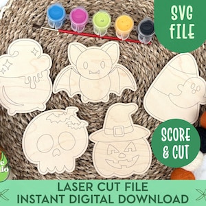 May include: Wooden Halloween-themed cutouts, including a cauldron, bat, candy corn with a ghost, skull, and jack-o'-lantern. The image includes paint pots, a paintbrush, and text that reads "SVG FILE", "SCORE & CUT", and "LASER CUT FILE INSTANT DIGITAL DOWNLOAD".