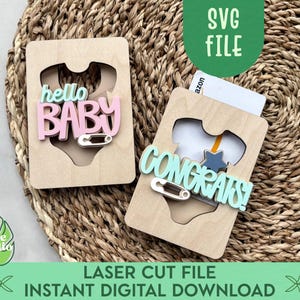 May include: Two wooden baby gift card holders with cut-out onesie shapes. One says "hello BABY" in pink and light blue, the other says "CONGRATS!" in light blue. Both have a safety pin detail. The image also includes the text "SVG FILE" and "LASER CUT FILE INSTANT DIGITAL DOWNLOAD".