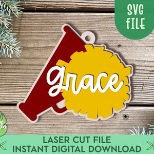 Op de afbeelding: Een rode megafoon met een gele pompon en het woord "grace" in witte letters. Dit is een digitaal download voor een laser-snijbestand.