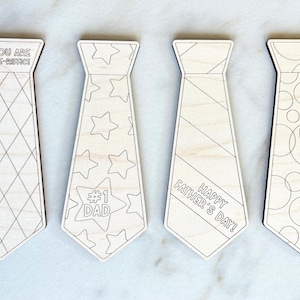 May include: Four wooden tie-shaped ornaments with various designs and text. One tie has a diamond pattern and reads "YOU ARE TIE-RIFFIC!". Another has stars and "#1 DAD". A third says "HAPPY FATHER'S DAY!". The last says "BEST DAD EVER".