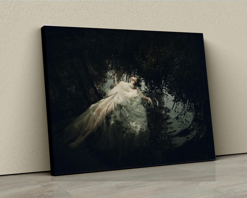 May include: A woman in a white dress lies in a dark, watery setting. The dress is flowing around her, and the water is reflecting the light from above. The scene is mysterious and ethereal.