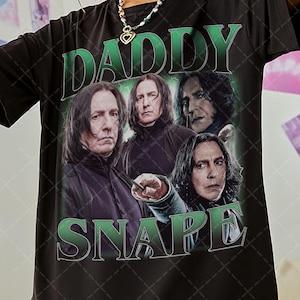 May include: Black t-shirt with a green graphic print of the character Severus Snape from the Harry Potter series. The graphic includes the text "Daddy Snape".