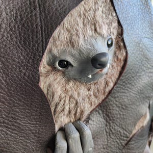 May include: A detailed close-up of a fantasy creature with a furry, gray and brown face, black eyes, and a small, black nose. The creature's hand, with gray claws, peeks out from a brown leather-like material.