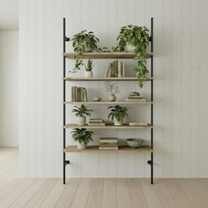 May include: A contemporary bookshelf featuring six wooden shelves supported by black metal frames. The shelves are adorned with potted plants, books, and decorative objects. The backdrop is a white panelled wall and light wood flooring.