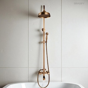 May include: Antique bronze shower fixture with a round showerhead and handheld sprayer. The fixture includes a faucet and a curved water outlet, mounted on a vertical pipe. The showerhead is positioned above a white bathtub.