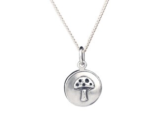 May include: A silver necklace with a round pendant featuring a detailed mushroom design.