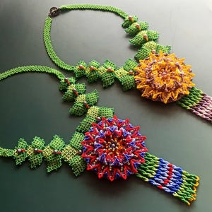 Könnte beinhalten: Zwei Perlenketten mit grünen Blattdesigns und bunten Blumenakzenten. Die Blumen sind aus Perlen gefertigt und haben einen 3D-Effekt.