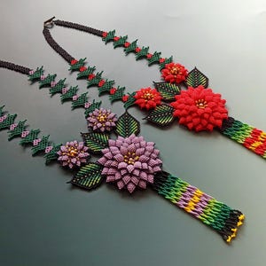 May include: Two beaded necklaces with floral designs. One necklace features a large red flower, while the other has a purple flower. Both necklaces have green leaves and beaded accents in various colors.