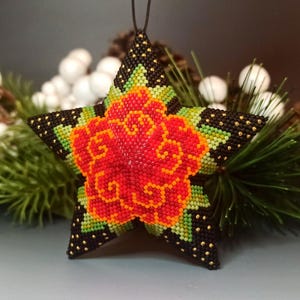 May include: A beaded star-shaped Christmas ornament with a red, orange, and green floral design. The star is black with gold accents.